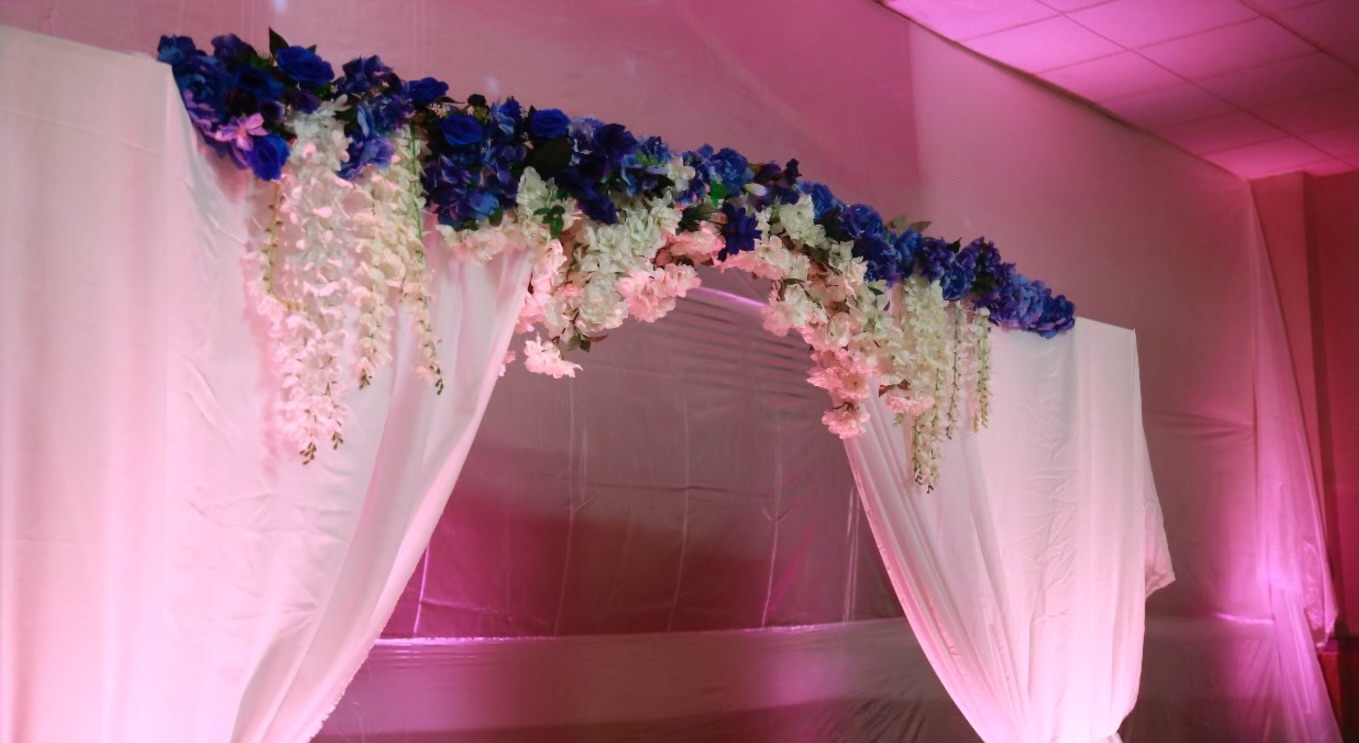 Close-up of florals over a white drape arch