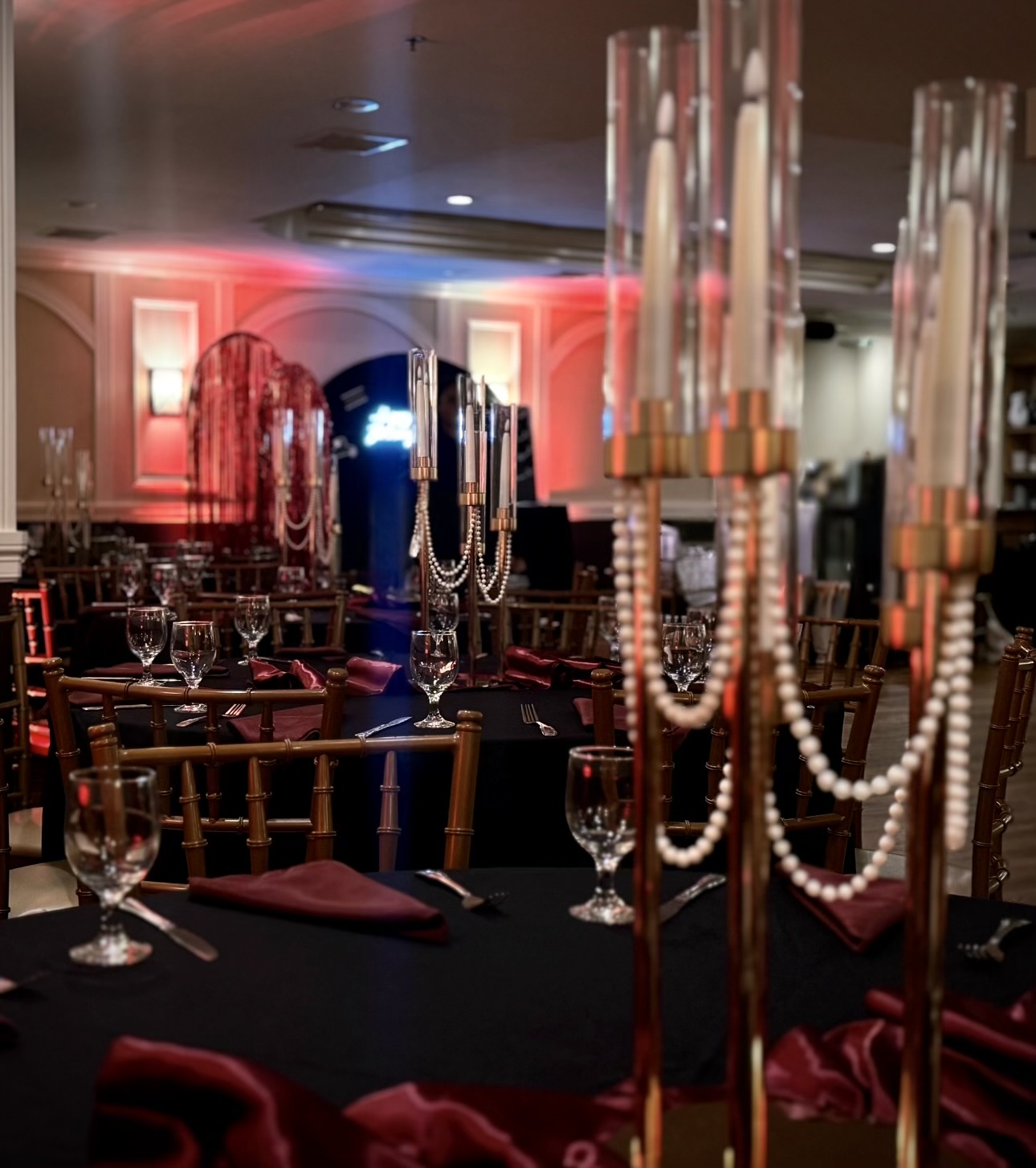 Tablescape with tall candles and pearl accents in red & gold lighting